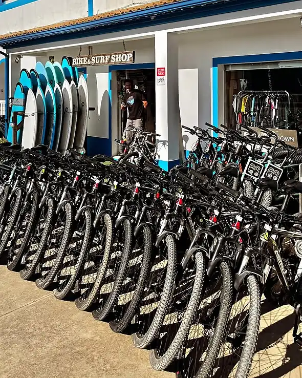 The rental fleet lined up outside the shop: long rows of bikes under the Bike & Surf Shop sign, with surfboards stacked by the door.